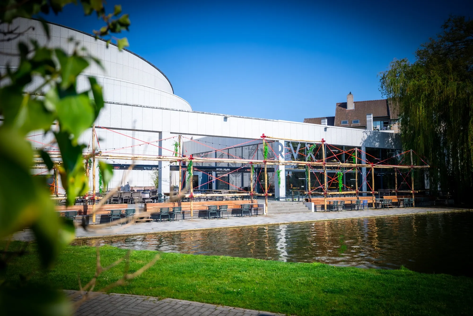 Het terras van Retro Velinx aan het water, met lichtslingers en houten tafels